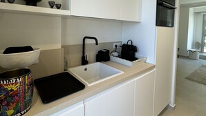 Una cocina moderna con armarios blancos, un grifo negro, un lavabo blanco y una encimera negra.