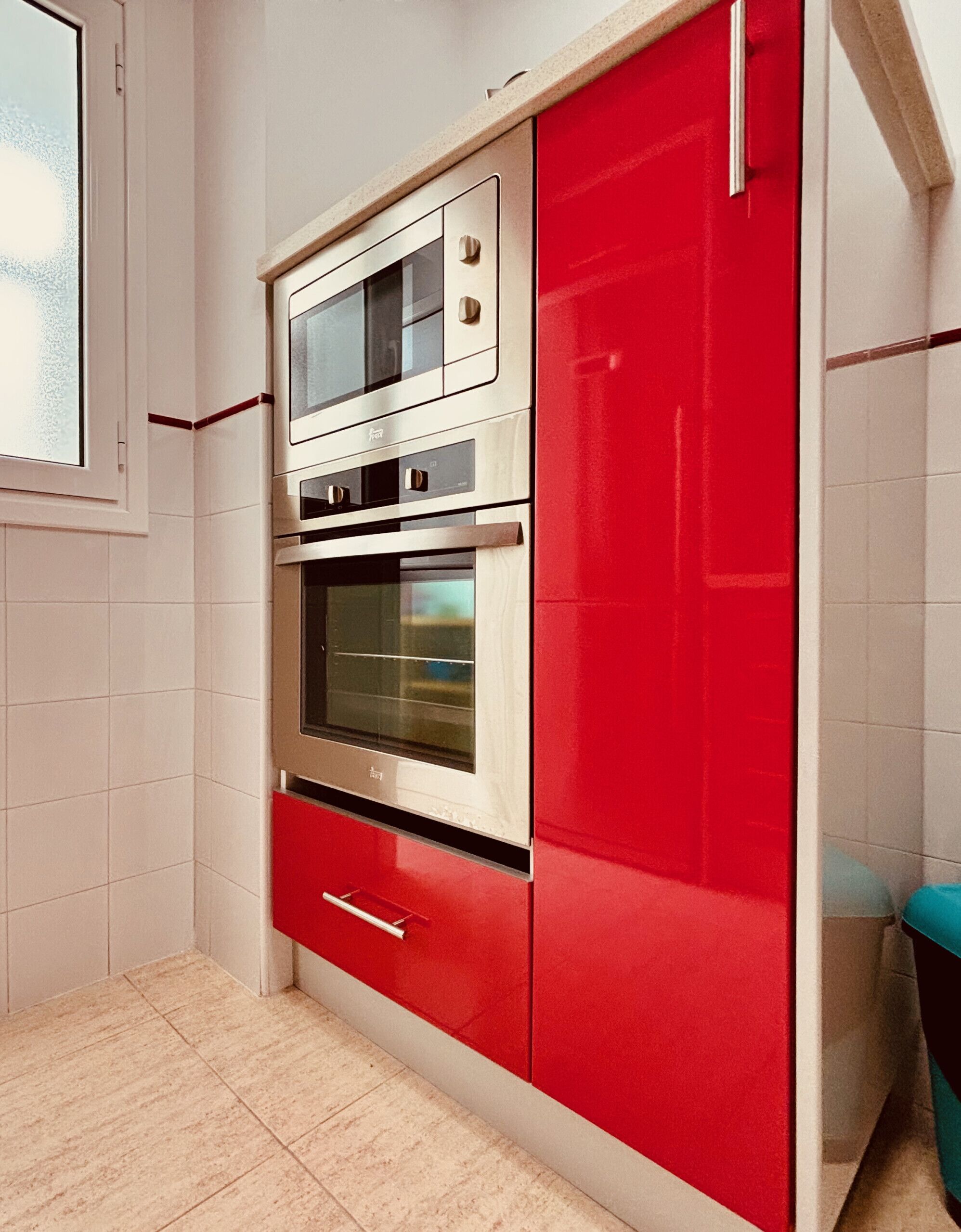 Una cocina con un armario rojo, un horno doble y un microondas.