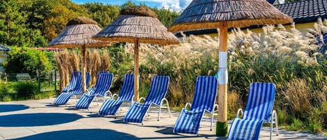 A poolside area with lounge chairs and thatched umbrellas.