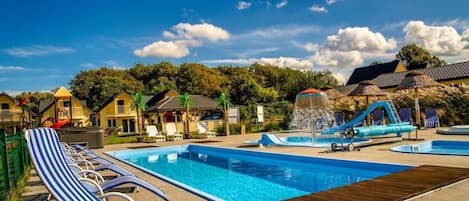 A swimming pool area with lounge chairs, a water slide, and a fountain.