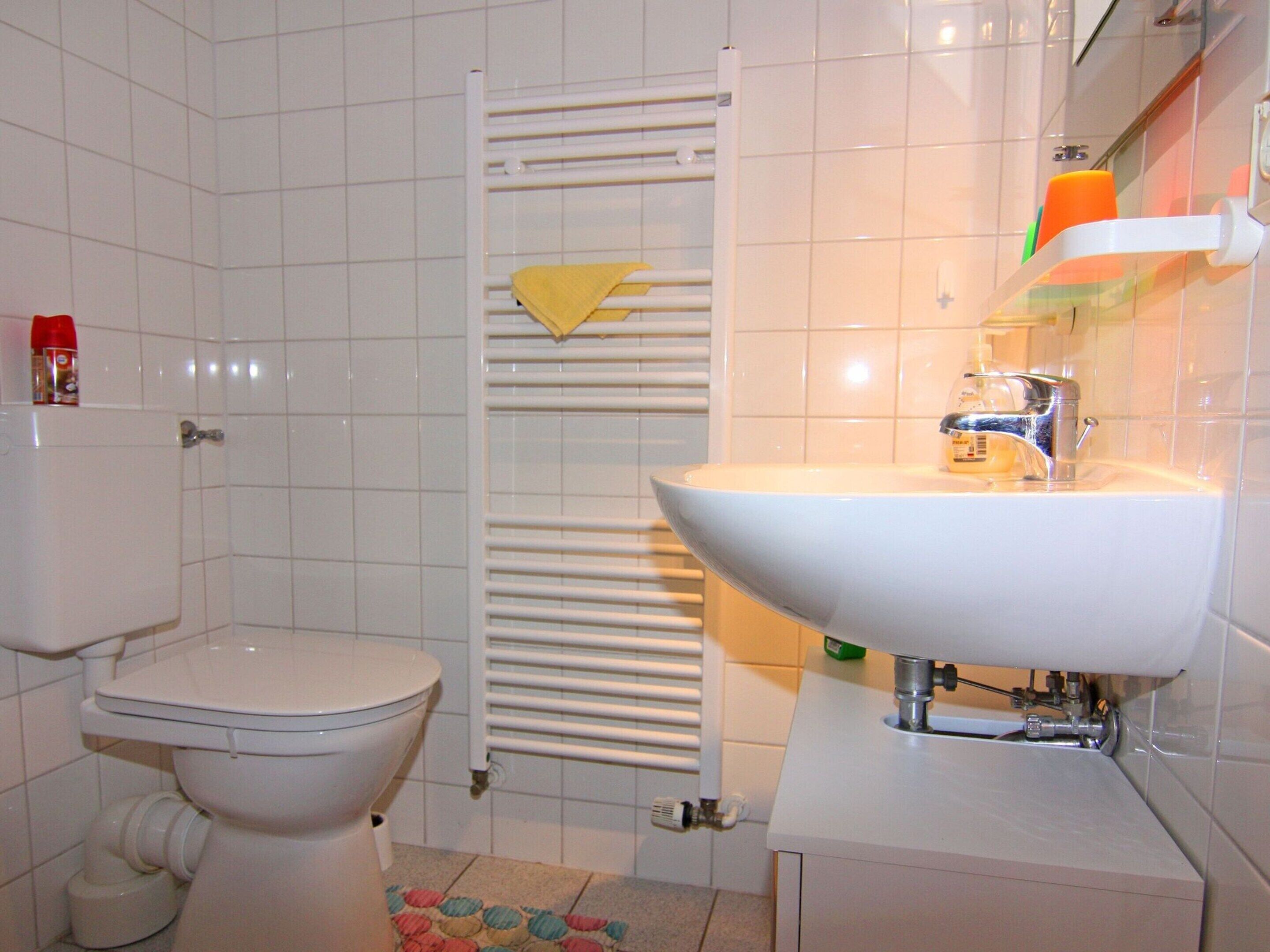 A bathroom with a toilet, a sink, and a towel rack.