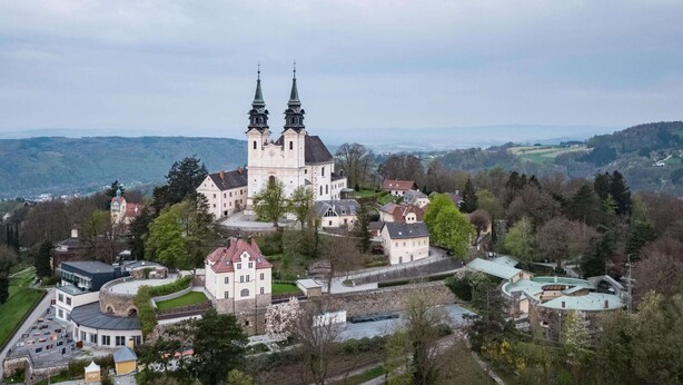 A historic castle with two prominent towers, surrounded by lush greenery and a hilly landscape. - Appartements Nicht Weit von der Donau (Linz)