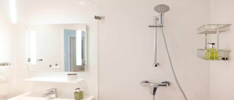A modern bathroom with a white sink, a handheld showerhead, and a wall-mounted shelf with toiletries.
