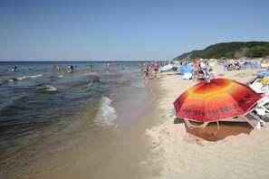 A beach with people swimming and walking along the shore, umbrellas, and beach chairs. - Holiday Home Near Baltic Sea and Nature Reserve (Kamien Pomorski)
