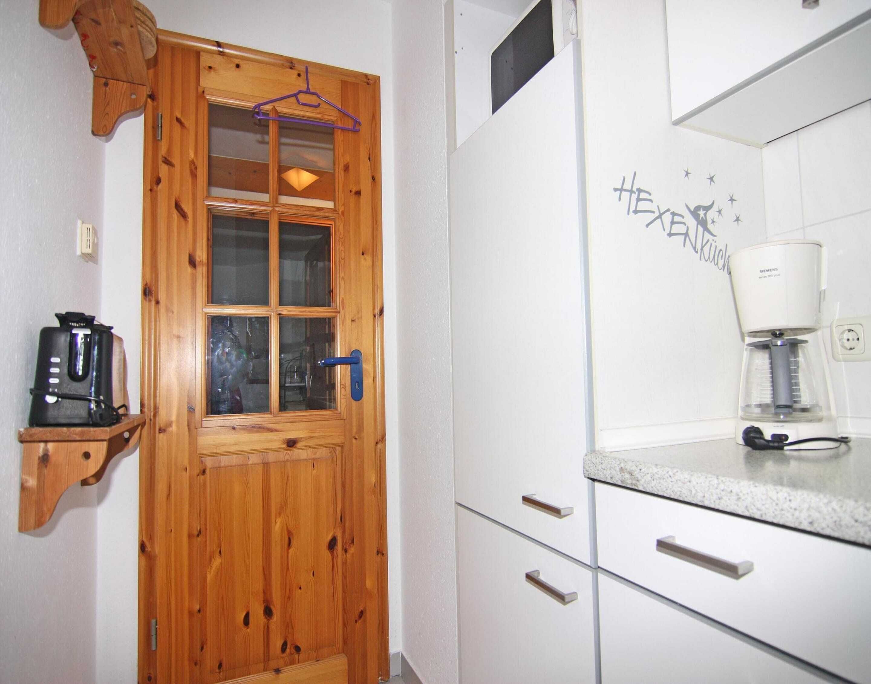 Una puerta de madera con un panel de vidrio, un perchero, una cafetera sobre la encimera y una pared con un diseño de estrellas.