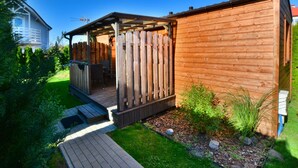 Une structure extérieure en bois dotée d’un espace salon couvert et d’une terrasse.