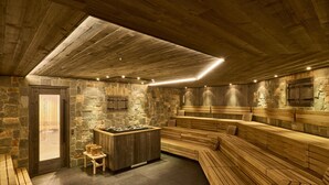 A sauna with wooden benches and a stone wall. - Apartment in Ischgl at the ski bus Stop (Ischgl)