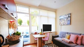 Ein gemütlicher Wohnraum mit Küchenzeile, Essbereich, Sofa und Fernseher.