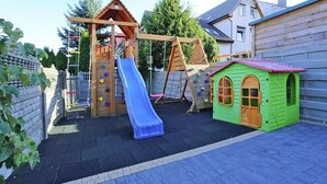 Ein Spielplatz mit Rutsche, Kletterwand und einem kleinen Spielhäuschen.