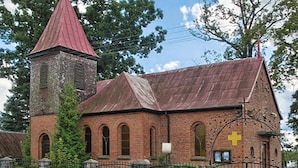 Eine Kirche mit rotem Kirchturm und einer Ziegel-Fassade.