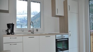 A modern kitchen with white cabinets, a built-in oven, and a coffee maker. - Chalet in Steeg Near Ski Slopes (Steeg)