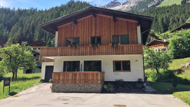 A two-story wooden building with a balcony, surrounded by greenery and mountains. - Chalet in Steeg Near Ski Slopes (Steeg)