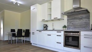 Una cocina moderna con armarios blancos, una campana extractora de acero inoxidable y un horno empotrado.