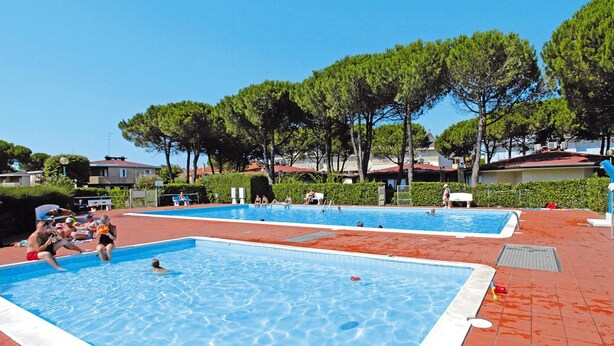 A swimming pool area with multiple pools and a red-tiled deck. - Holiday Village Tivoli in Bibione (San Michele al Tagliamento)