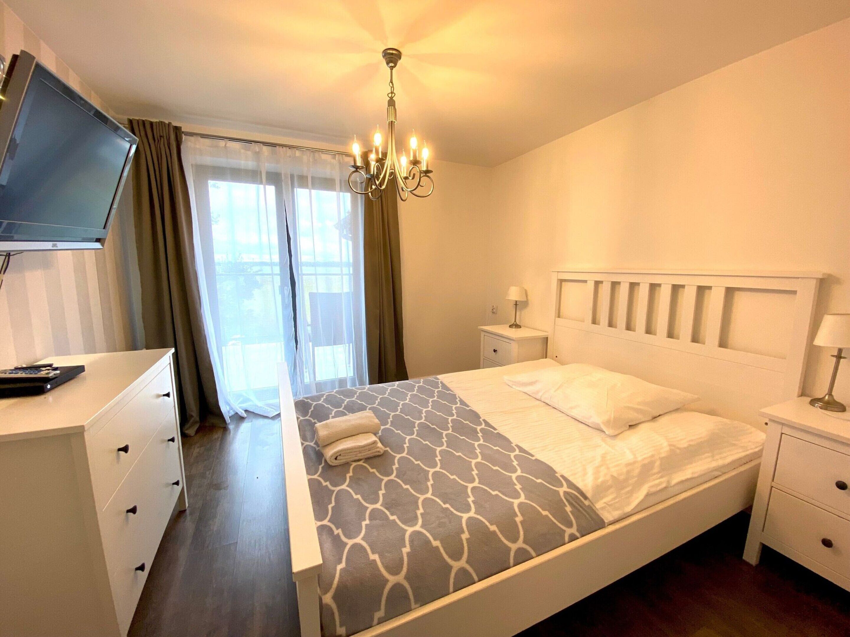 Ein Hotelzimmer mit Bett, Fernseher, Schreibtisch und einer Kristallleuchtre.