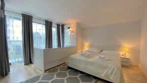 Une chambre à coucher avec un lit, des lampes de chevet, une fenêtre avec des rideaux et une vue sur l’extérieur.