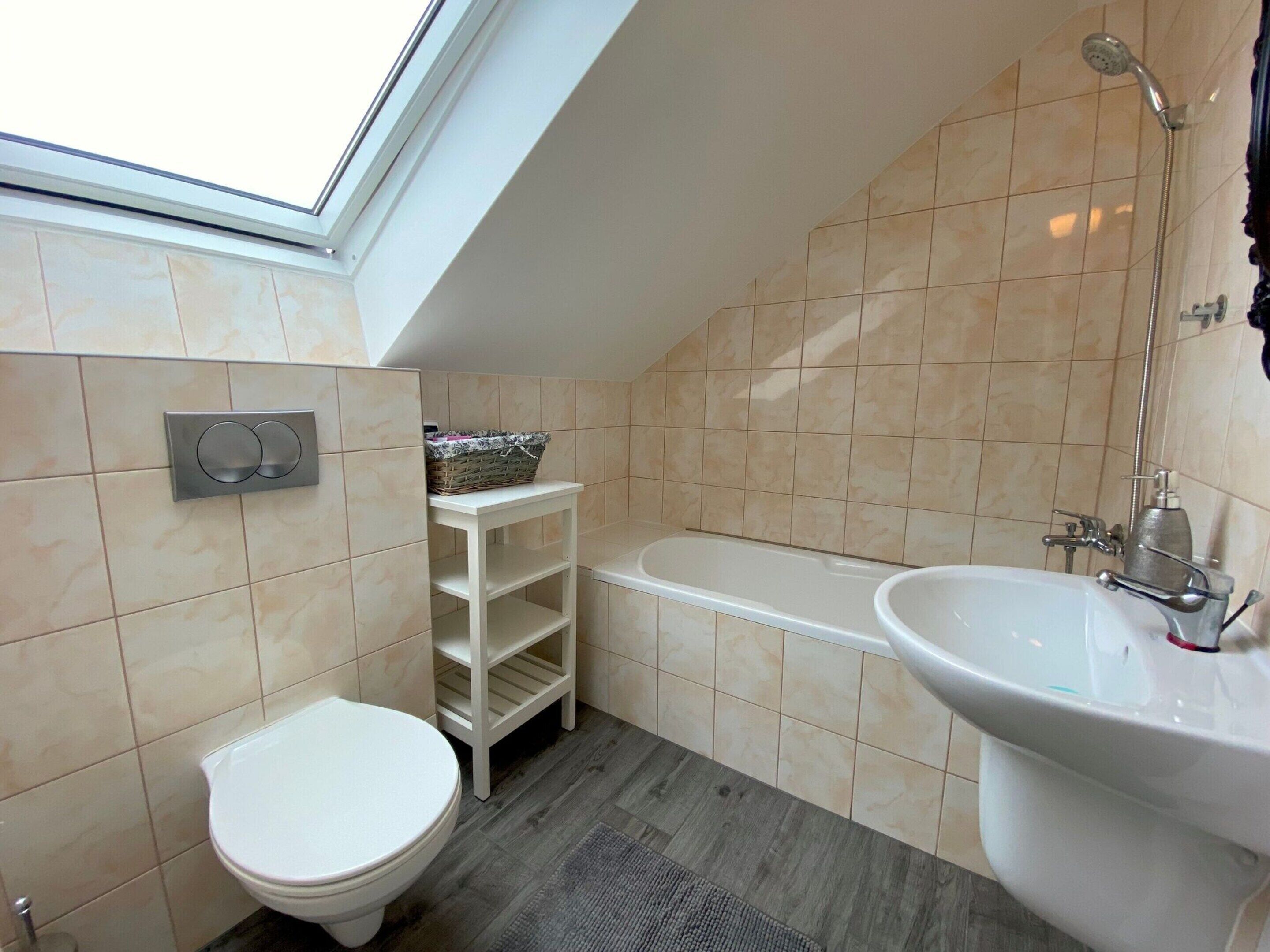 Ein Badezimmer mit Dachfenster, Toilette, Badewanne und Waschbecken.