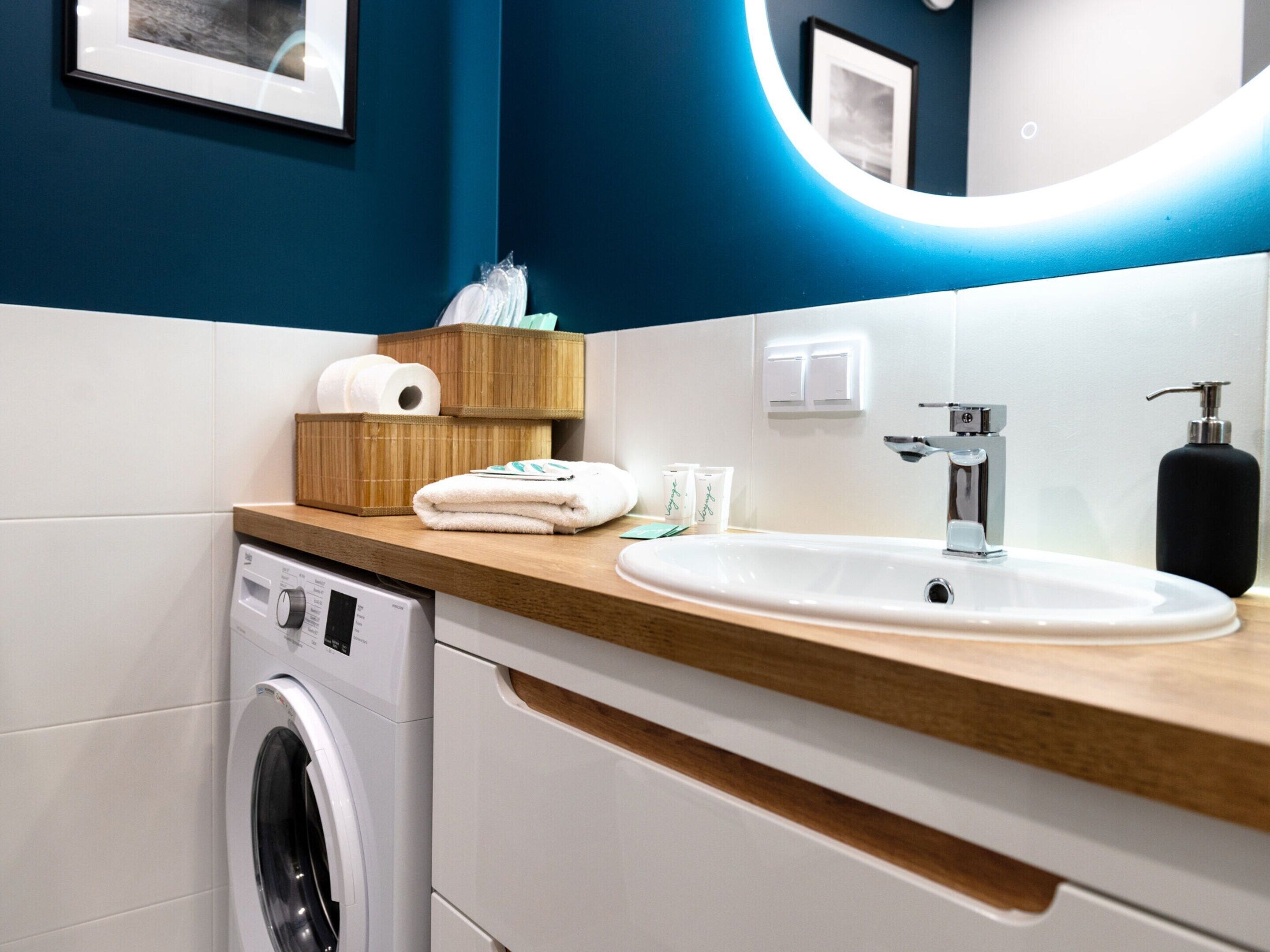 A modern bathroom with a washing machine, a sink, and toiletries.
