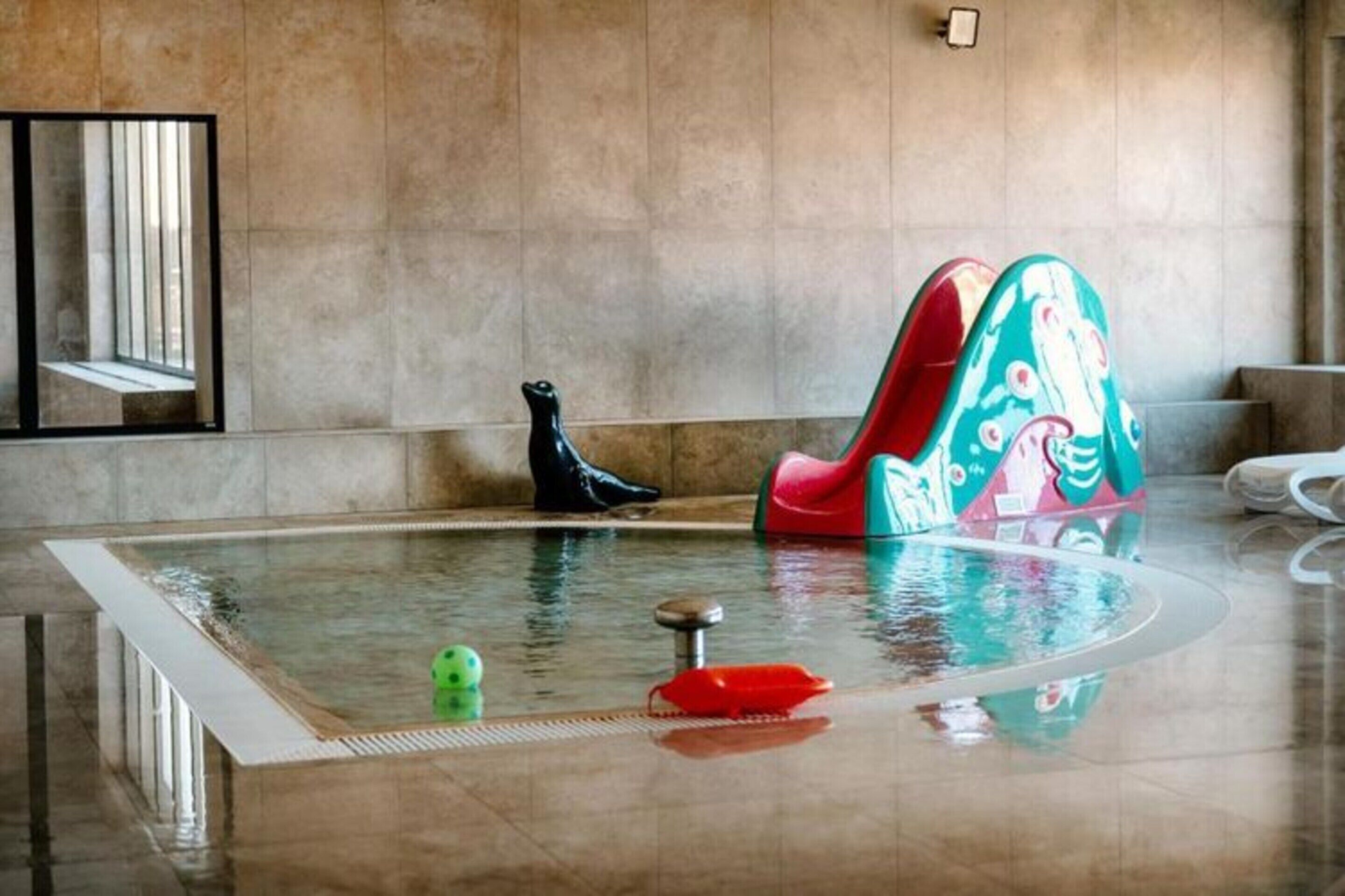 Ein Swimmingpool mit einem roten und grünen Stuhl, einem schwarzen Stiefel und einem grünen Ball.
