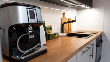 Une cuisine moderne équipée d’une machine à café intégrée, d’une planche à découper en bois et d’un évier en acier inoxydable.