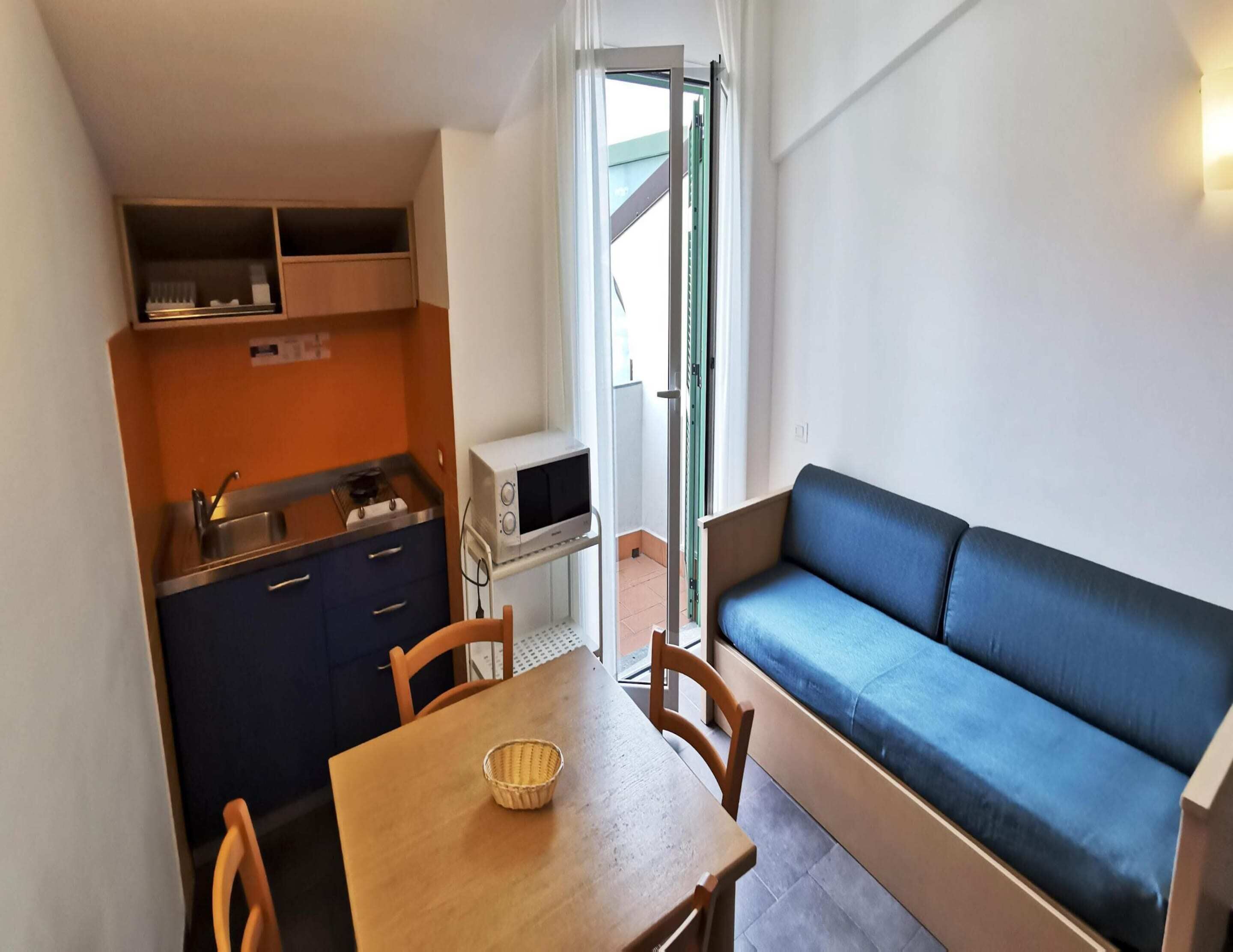 A compact kitchenette with a microwave, a sink, and a small dining area with a table and chairs.
