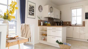 Una cucina moderna con pensili bianchi, un piano di lavoro in legno e un lampadario.