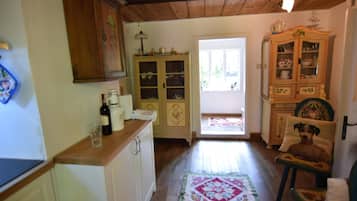 A kitchen with wooden cabinets, a dining table, and a chair. There is a window with a view of the outside.