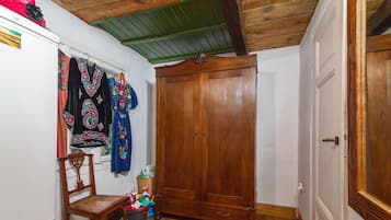 A room with a wooden wardrobe, a chair, a small table, and a red rug.