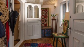 En gang med en hvid dør, gulvtæpper med et mønster og en stol med et farverigt design.