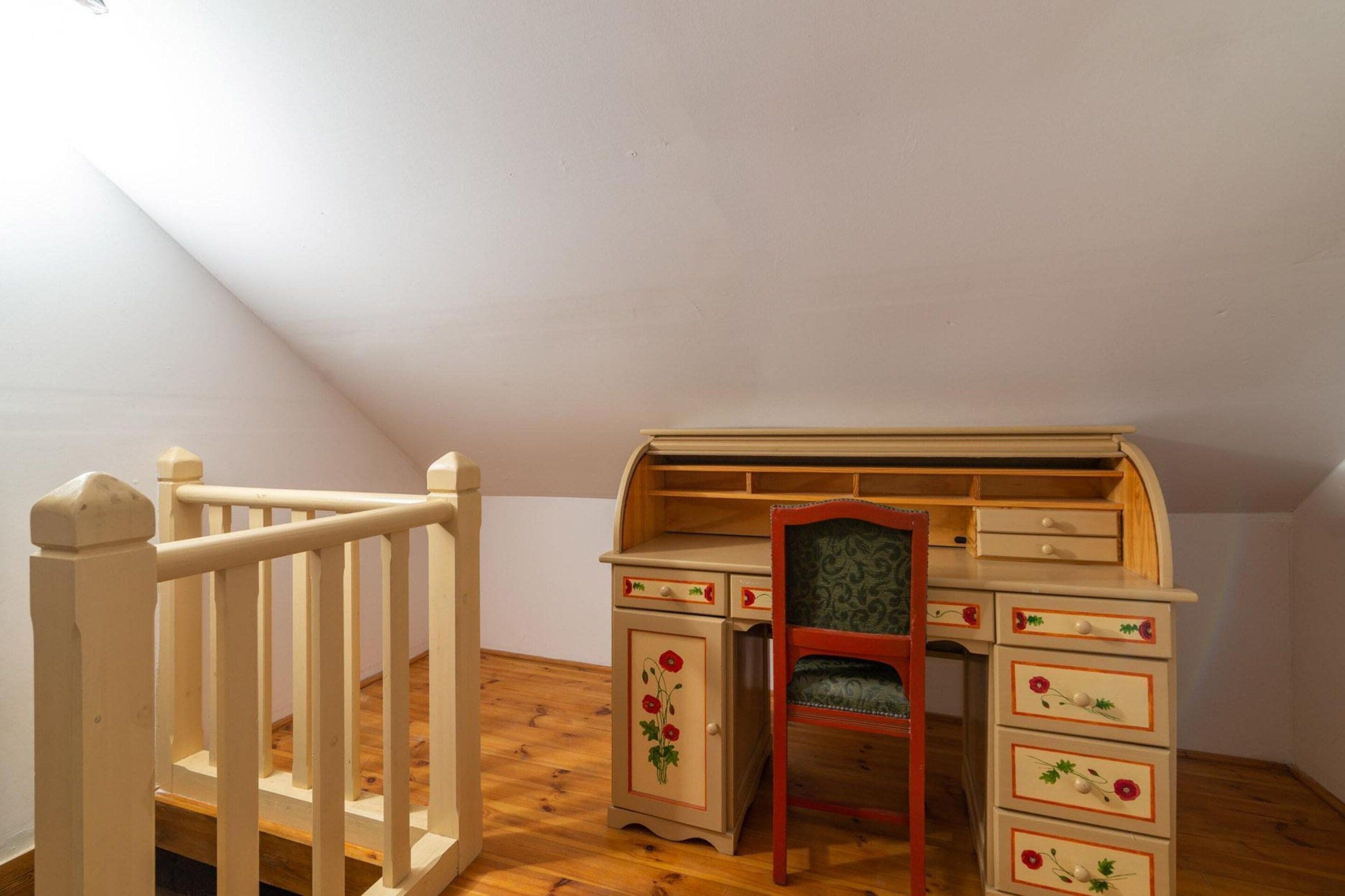 Une chambre d’enfant avec un bureau en bois, une chaise et un petit lit.