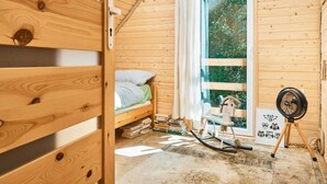 Acogedora habitación de cabaña de madera con cama, una mecedora y un ventilador.