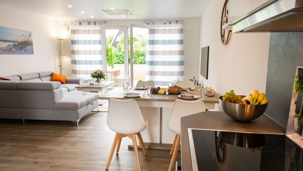 Una cucina moderna con zona pranzo, divano e vista su spazi verdi.