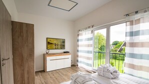 Una camera da letto con un letto grande, un'armadio in legno, un comodino, un quadro e vista su un giardino attraverso una finestra con tende a righe.