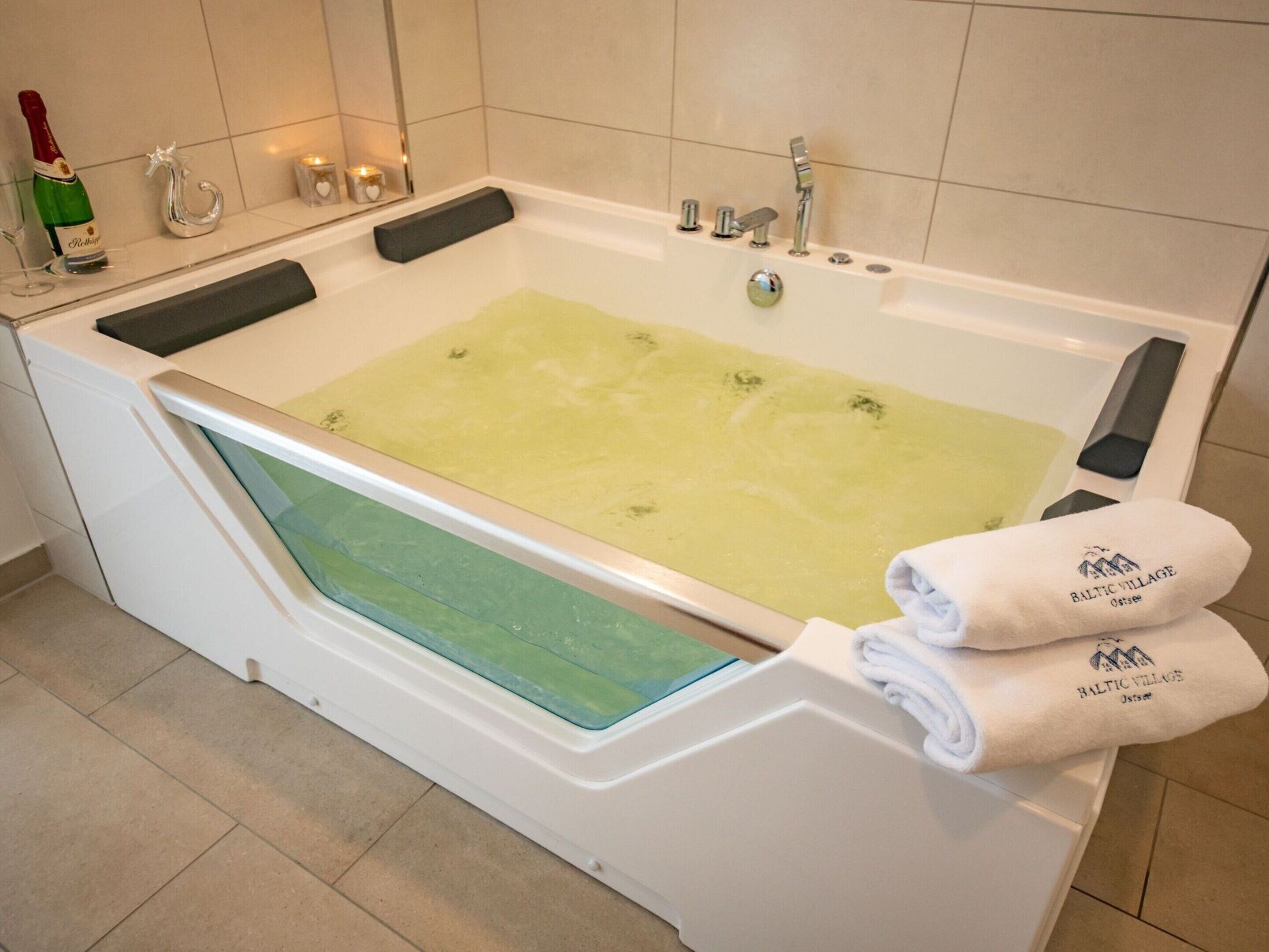 A modern bathroom with a bathtub, a glass-enclosed shower, and a towel rack with towels.