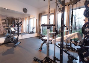 A gym with exercise equipment, large windows, and a mirror. - Holiday Home With Sauna and Jacuzzi (Damp)