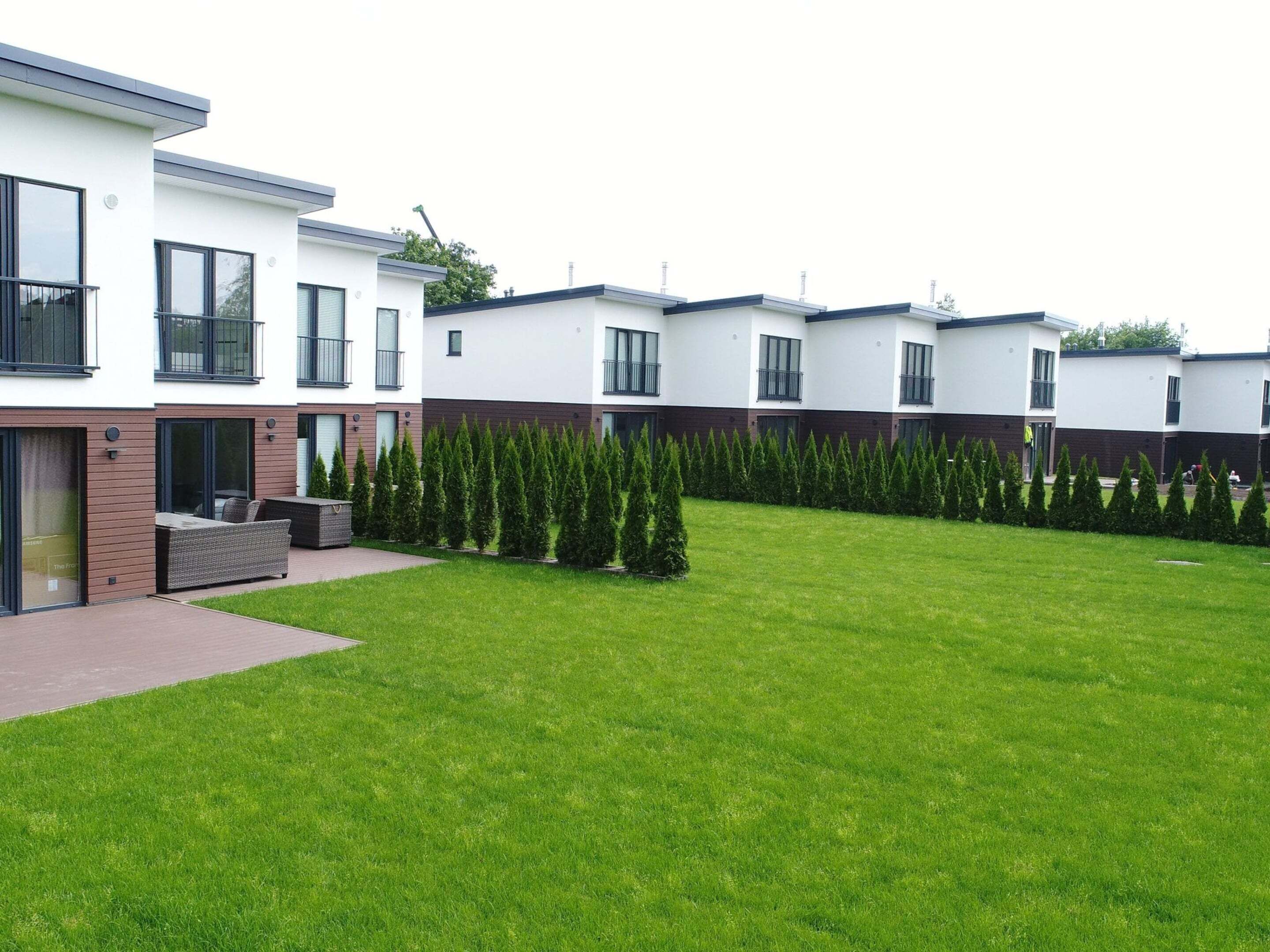 A modern residential building with a well-maintained lawn and neatly trimmed hedges.
