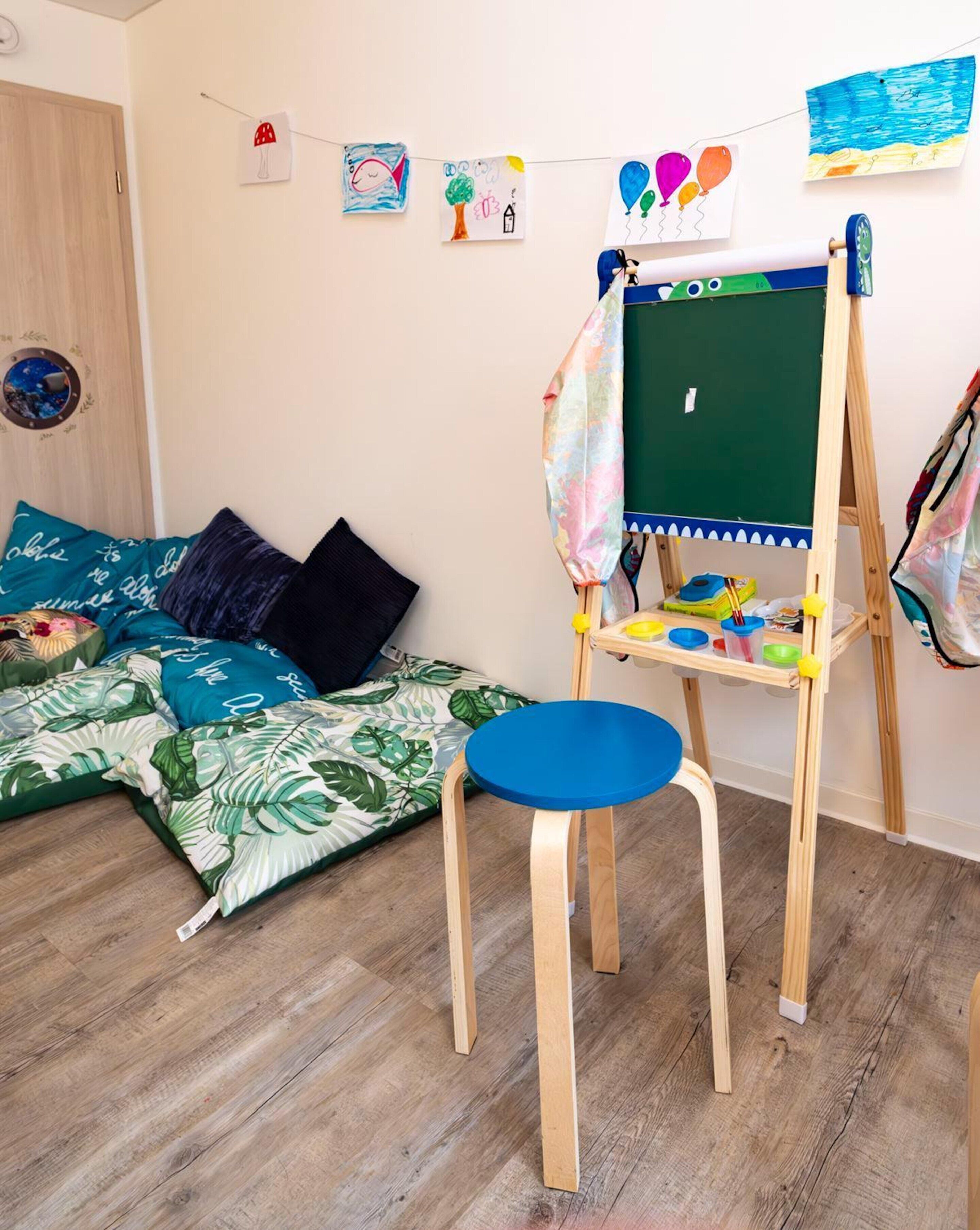 Ein gemütliches Zimmer mit Holzboden, einer grünen Kreidetafel und einem kleinen Holzstuhl.
