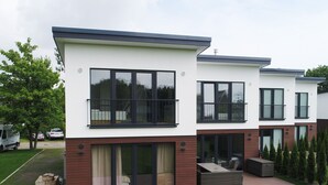 Un edificio residenziale moderno su due piani, con ampie finestre, balconi e una zona patio coperta.