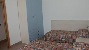 Ein Schlafzimmer mit blauem Kleiderschrank, zwei Betten mit gemusterten Bettbezügen und einem weißen Kopfteil.