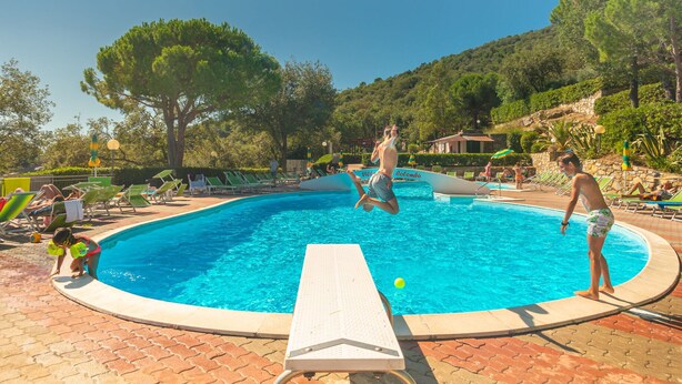 A swimming pool area with lounge chairs and a diving board. - Holiday Complex With Pool in Andora (Andora)