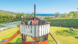 A playground with a slide and climbing structures, set against a backdrop of a clear sky and distant hills. - Holiday Complex With Pool in Andora (Andora)