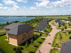 A residential area with a large building labeled "Seepark Auerhain" featuring a tiled roof, surrounded by well-maintained lawns and a pathway leading to a body of water. - Seepark Auenhain am Markkleeberger See in Markkleeberg (Markkleeberg)