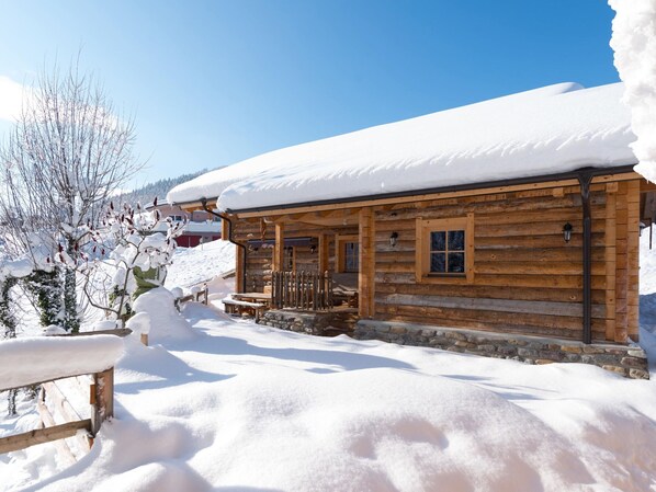 A wooden cabin with a stone foundation, surrounded by snow-covered ground and trees. - Chalet in St. Martin With Sauna & Hot Tub (Sankt Martin am Tennengebirge)