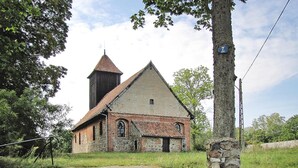 A church with a bell tower, a stone wall, and a sign indicating the number 7. - Cottage by Lake Dabrowa With Fishing (Dabrówno)
