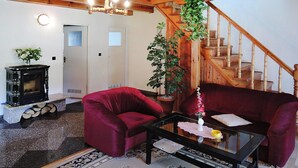 A living room with a red sofa, a glass coffee table, a fireplace, and a staircase. - Cottage by Lake Dabrowa With Fishing (Dabrówno)