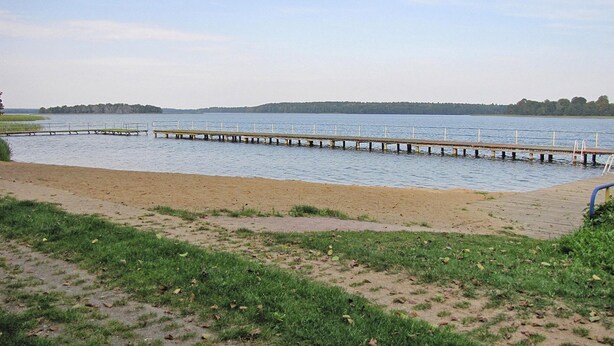 A sandy beach with a wooden pier extending into calm water. - Cottage by Lake Dabrowa With Fishing (Dabrówno)