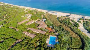 An aerial view of a coastal property with a swimming pool, beach access, and dense greenery. - Residence Baia Verde, Valledoria (Valledoria)