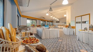 A breakfast buffet with various food items and bread, a coffee station, and a seating area with tables and chairs. - Residence Baia Verde, Valledoria (Valledoria)