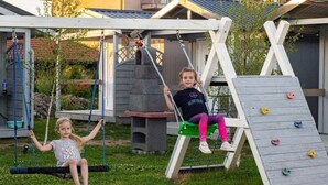 Un’altalena in legno con una parete di arrampicata in un giardino.