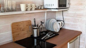 Una cucina con forno a microonde, macchina del caffè e utensili sul bancone.